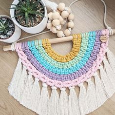 a multicolored crocheted rug with tassels next to potted succulents