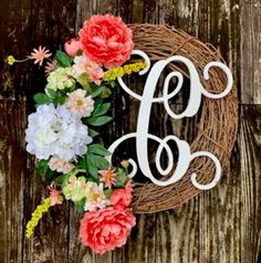 a monogrammed wreath with flowers and the letter f on it is hanging on a wooden wall