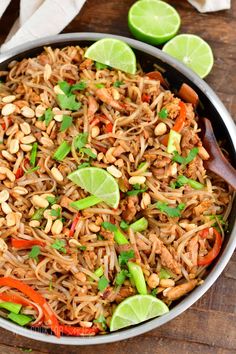 a bowl filled with rice and vegetables on top of a wooden table next to limes