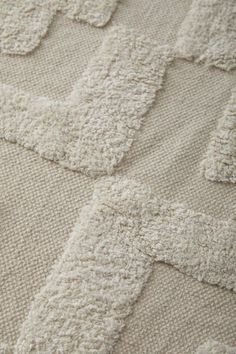 a close up view of a white rug with squares and crochets on it