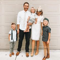 a man, woman and two children standing in front of a garage door with their arms around each other