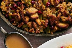 a pan filled with stuffing and cranberries next to a cup of coffee