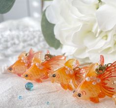 four glass goldfish figurines sitting next to a white flower