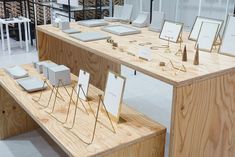 a wooden table topped with lots of white boxes and frames next to shelves filled with books