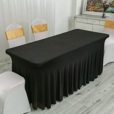 a black table with white chairs around it and a painting on the wall behind it