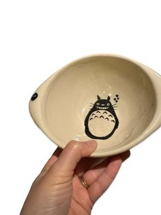 a hand holding a bowl with a totoro drawn on it