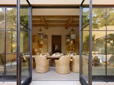 an open glass door leading into a dining room with wicker chairs and tables in it