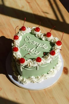 a birthday cake with white frosting and cherries sitting on top of a wooden table