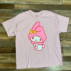 a pink hello kitty t - shirt sitting on top of a wooden floor