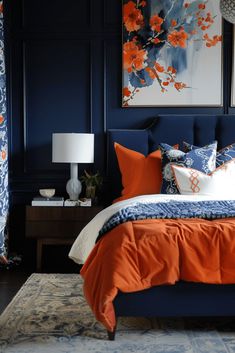 a bedroom with blue walls and orange bedding in the center, along with two paintings on the wall