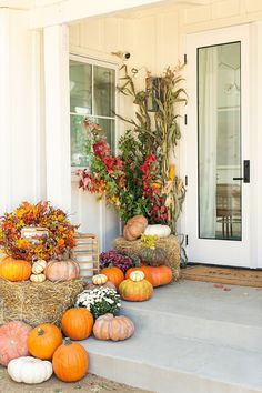 pumpkins and gourds on the front steps of a house