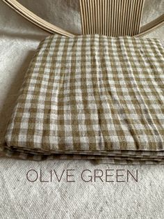 a bed with a checkered blanket and pillow on it's side, next to the words olive green