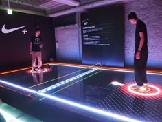 two young men standing on top of a table with neon lights in front of them