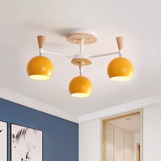 three yellow lights are hanging from the ceiling in this blue and white room with pictures on the wall