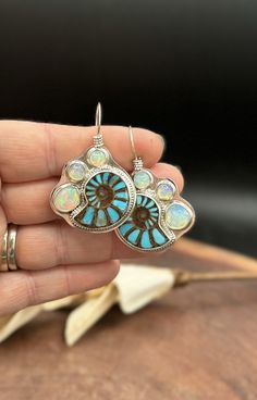 Ammonite with bright Turquoise inlay set on sterling silver landings and wrapped with silver beaded wire. These stones are incredible! The inlay gives so much depth to the Ammonite and the color is beautiful. Three Opals are set along the side bringing iridescent colors and a little sparkle to these stunners. These earrings are handmade and one of a kind. Measurements Length 2 inches Width 1.25 inches Turquoise Spiritual Jewelry With Matching Earrings, Turquoise Inlay Sterling Silver Jewelry, Unique Turquoise Nickel-free Jewelry, Sterling Silver Turquoise Inlay Jewelry, Spiritual Turquoise Sterling Silver Earrings, Unique Turquoise Jewelry With Inlay, Southwestern Silver Earrings With Natural Stones, Turquoise Inlay Earrings Gift, Turquoise Inlay Earrings As Gift