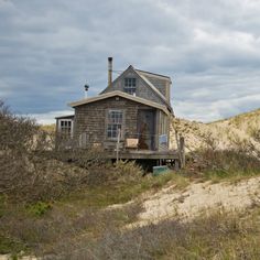 a small house sitting on top of a sandy hill