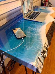 a laptop computer sitting on top of a blue table covered in frosty water and sand