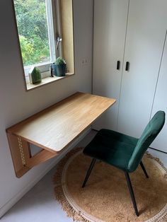 a green chair sitting in front of a window next to a wooden desk and cabinet