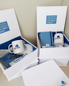 two open boxes with coffee mugs and notebooks in them, sitting on a table