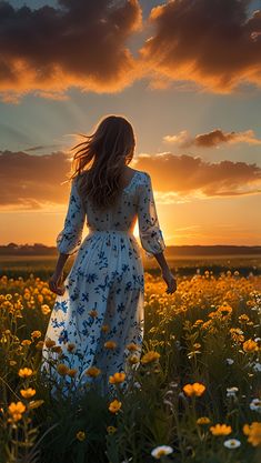 a woman in a white dress walking through a field with yellow and white flowers at sunset