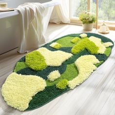 a green and white rug on the floor in a room with a tub, toilet and window