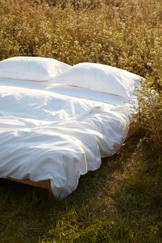 an unmade bed sitting in the middle of a field