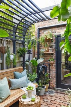 a wooden bench sitting under a pergolated roof next to a brick wall and potted plants