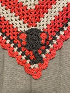 a crocheted square with an elephant on it's center and red, black, white, and gray squares