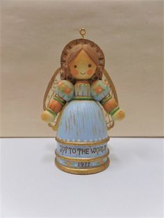 a ceramic angel figurine sitting on top of a blue ball with the words happy to the world