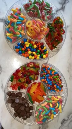 three plastic trays filled with different types of candies on a marble counter top