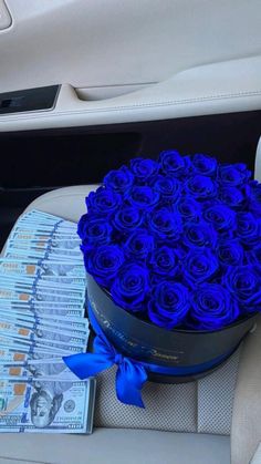 blue roses in a round box sitting on the back seat of a car next to a stack of money