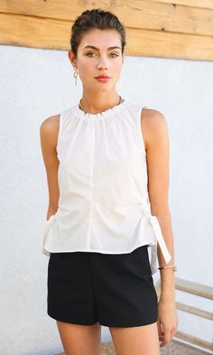 Crisp poplin, cut and gathered into an elegant, sleeveless top. Featured on the sides are O-ring cut outs, adjustable with ribbons. The collar is lined with elastic, creating a ruffled detail and adding texture to the garment. The top can be easily elevated with trousers and your favorite jewelry. Poplin top Side cutouts Self ties Center seam Self: 100% Cotton Length: 21 1/2" Chest: 18 3/8" Hand wash in cold water. Lay flat to dry. Low iron. Model is wearing a size small Style #: G235T6800 Edgy Minimalist, Ring Cuts, Capsule Wardrobe Essentials, Cutout Top, Poplin Top, Cut Out Top, Low Iron, Cut Outs, O Ring