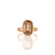 a ring with an orange stone in the center and a gold band around it, on a white background