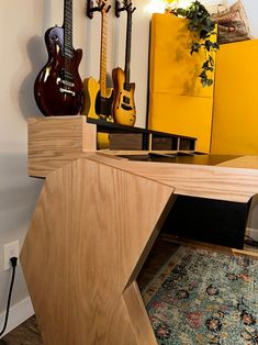 guitars are lined up on the wall next to a table with a guitar stand in front of it