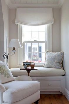 a white couch sitting under a window next to a lamp