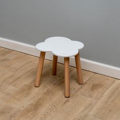 a small white table sitting on top of a hard wood floor next to a wall