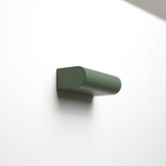 the corner of a white wall with a green object on it