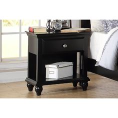 a night stand with an alarm clock on top and a drawer underneath it in a bedroom