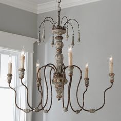 a chandelier with candles hanging from it's arms in front of a window