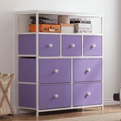 a purple and white dresser with drawers in a room next to a chair on the floor