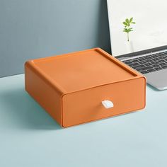 an orange box sitting on top of a desk next to a laptop computer and mouse