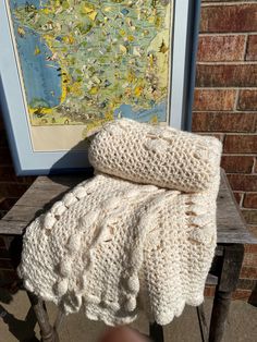 a blanket sitting on top of a wooden bench next to a brick wall with a map in the background