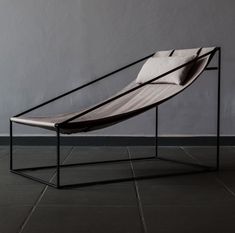 a chair sitting on top of a tiled floor next to a gray wall with a black frame