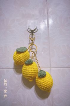 two crocheted lemons hanging from a keychain on a tile floor