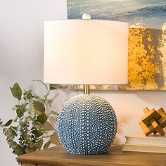 a blue vase sitting on top of a wooden table next to a lamp and books