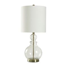 a glass table lamp with a white shade on the base and a gold metal base