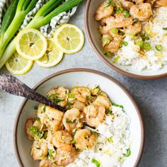 two bowls filled with shrimp and rice on top of a table next to lemon wedges