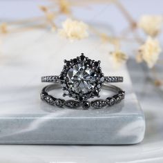 a diamond ring on top of a marble slab with flowers in the background and white petals