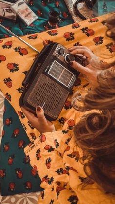 a woman laying on top of a bed holding a radio