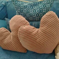 two heart shaped pillows sitting on top of a blue couch